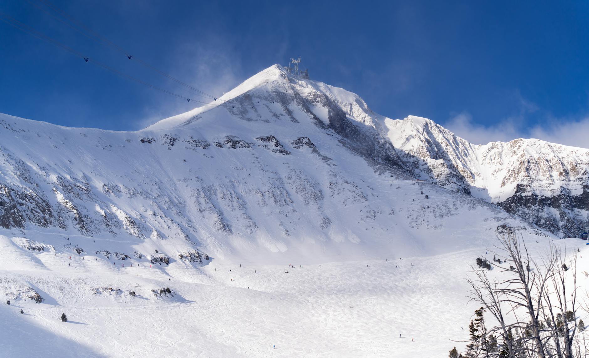 Capture of skiers on a snowy mountain under the clear blue sky in Montana, USA.