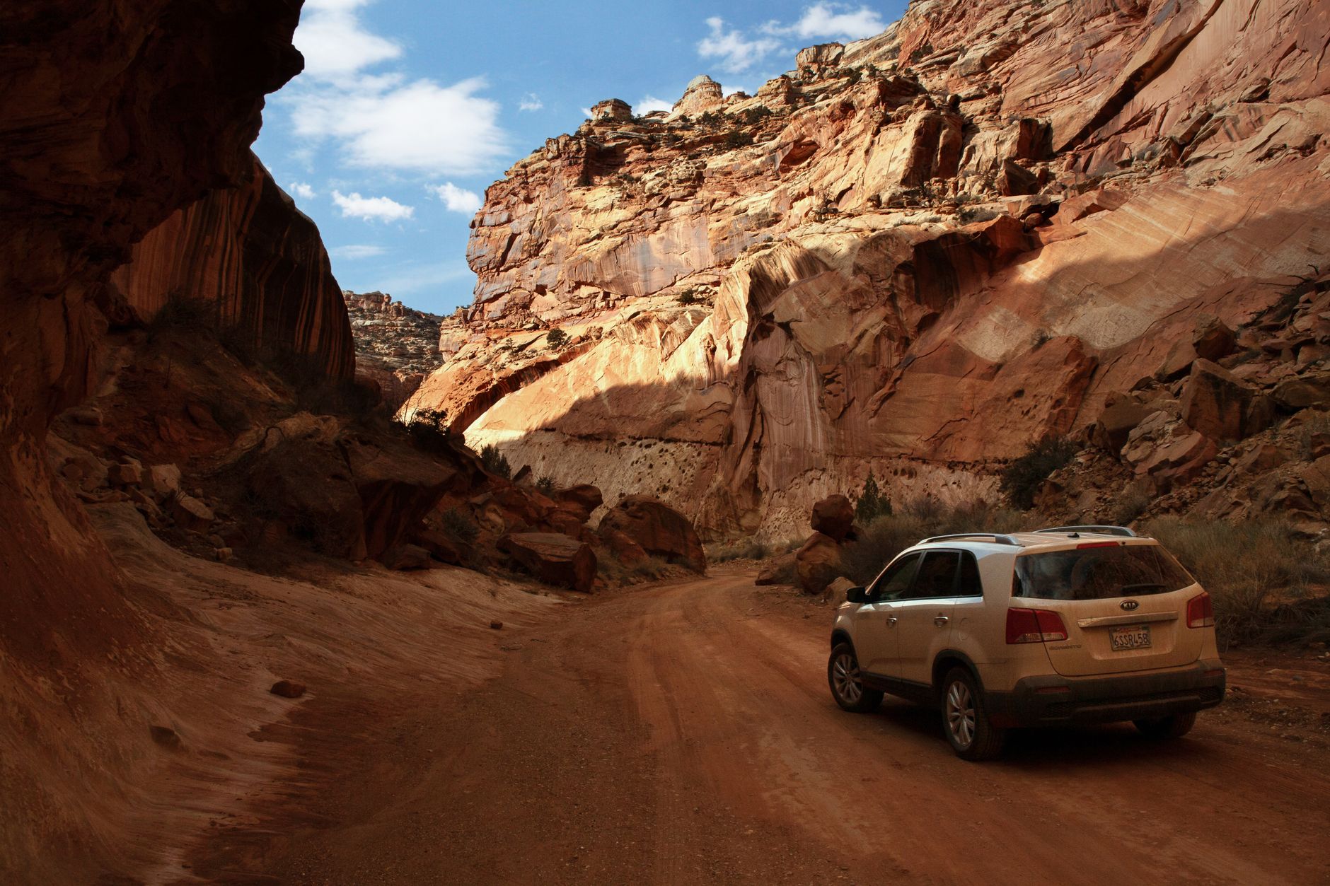 Explore the majestic Capitol Reef National Park with an SUV navigating a scenic dirt road through red rock canyons.