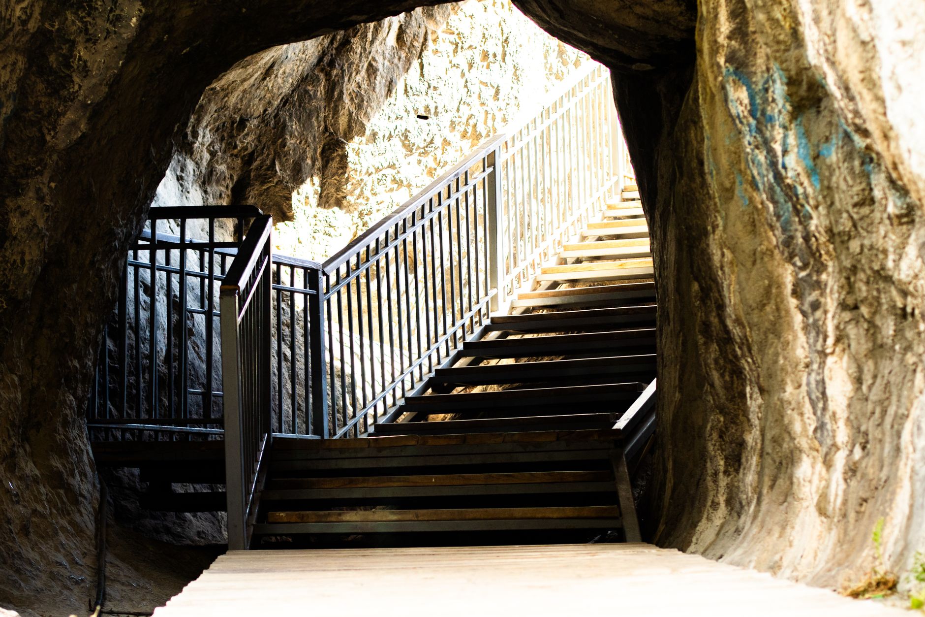 A metal staircase inside a cave illuminated by natural light, creating a sense of discovery.