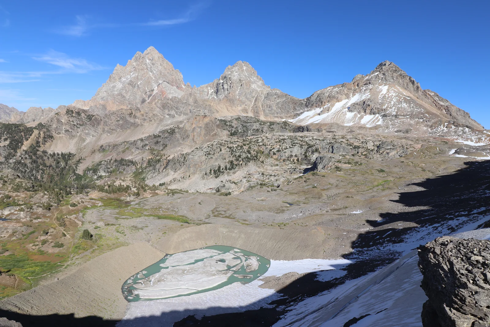 3 mountain peaks stand tall above a glacially carved valley, a glacial lake, and a small glacier.