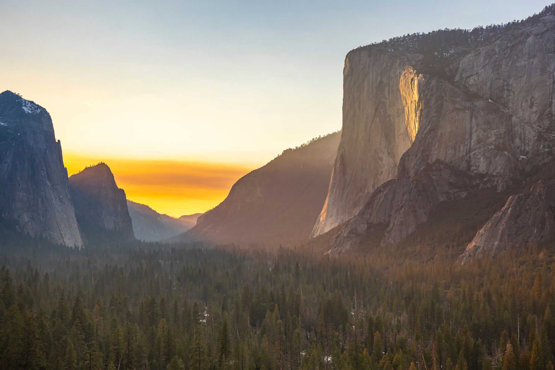 Majestic sunrise over Yosemite Valley with El Capitan and forest view, capturing natural beauty.