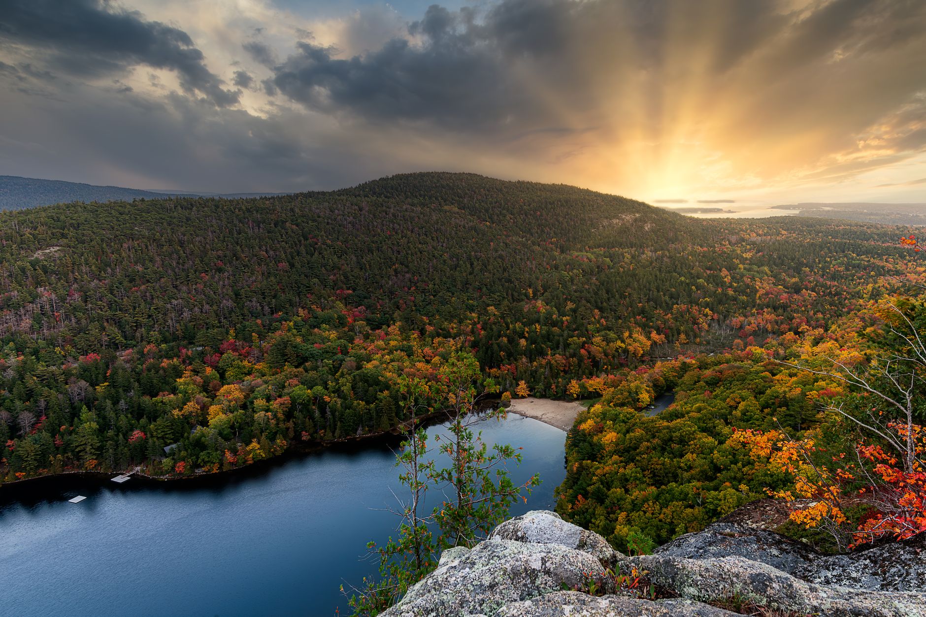 Picturesque scenery of autumn forest trees growing near calm river water against cloudy sunset sky