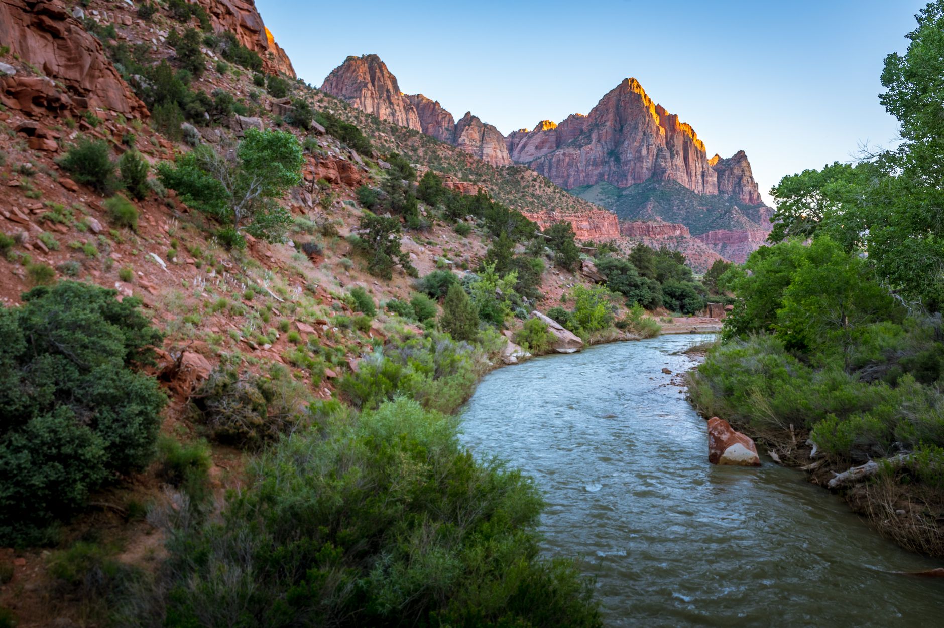 Stunning landscape of Virgin River in Zion National Park at sunset with towering canyon walls.
