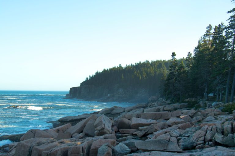 Stunning view of the rocky Acadia coastline with ocean waves crashing against the shore at sunrise.