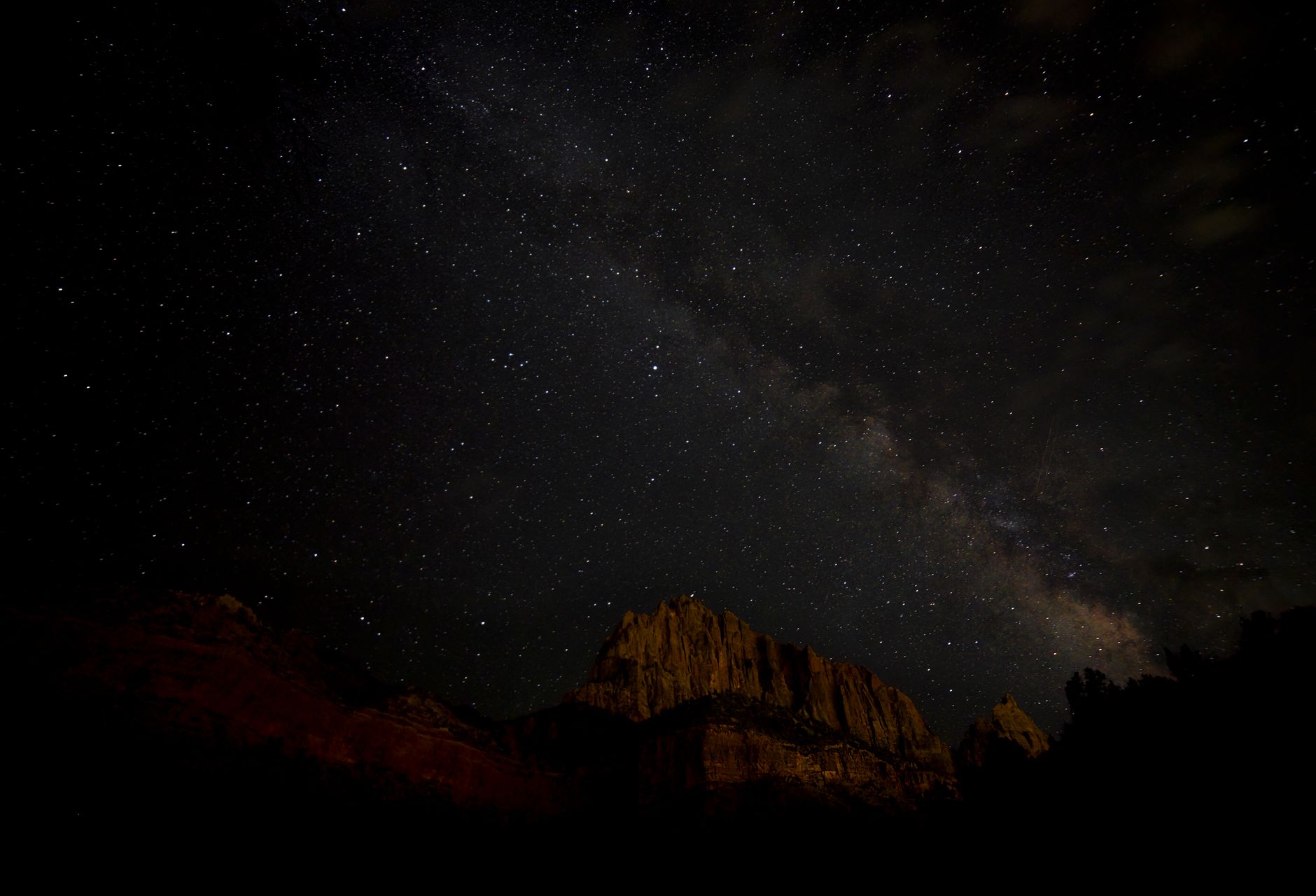 A breathtaking view of the Milky Way galaxy above a mountainous landscape at night.