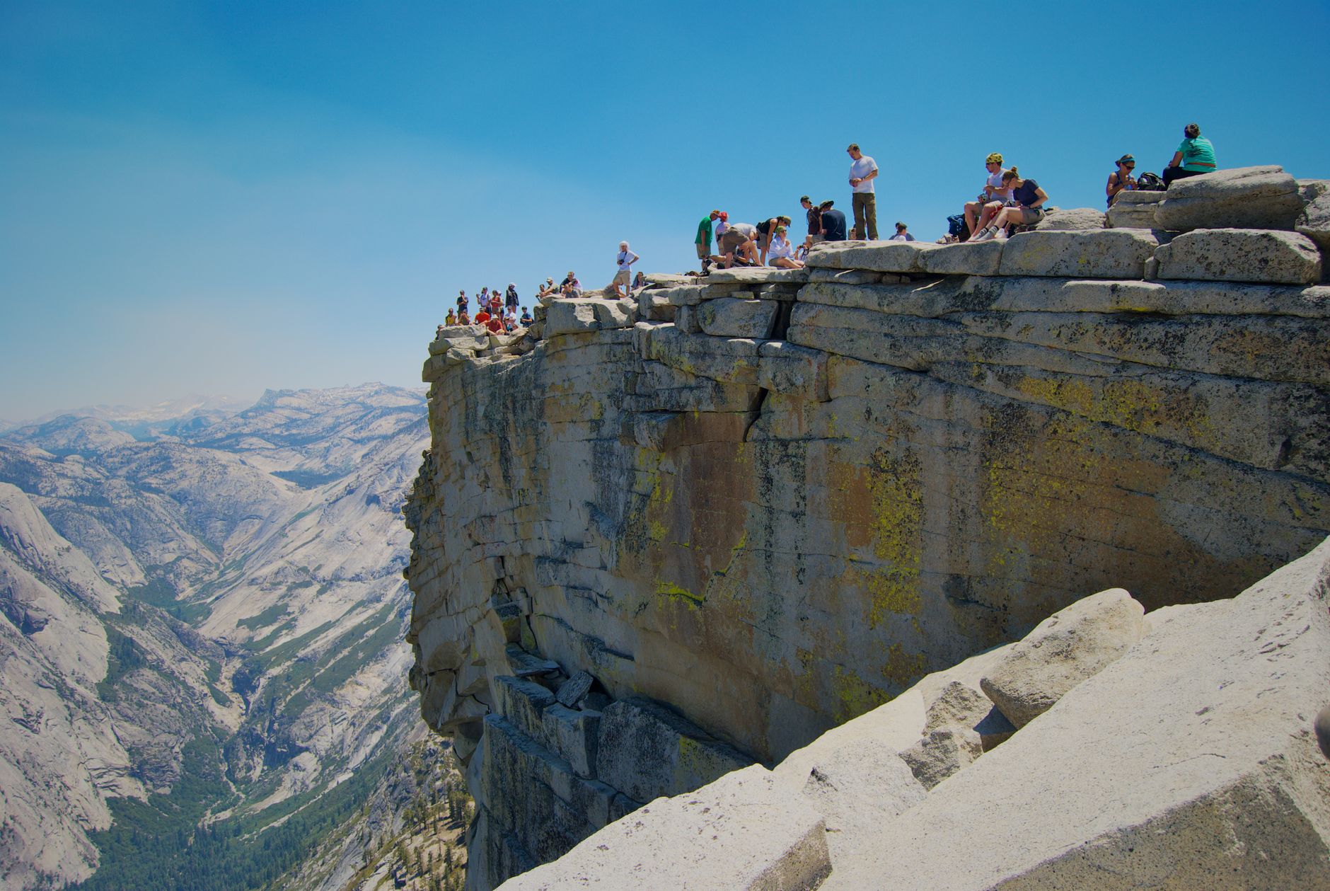 Hikers on the summit of Half Dome in Yosemite National Park, California, with stunning views.
