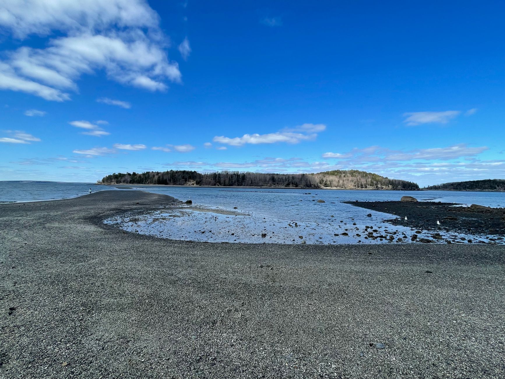 Rocky sandbar leading to a small island under a blue sky in Bar Harbor, Maine, USA. Perfect for nature lovers.