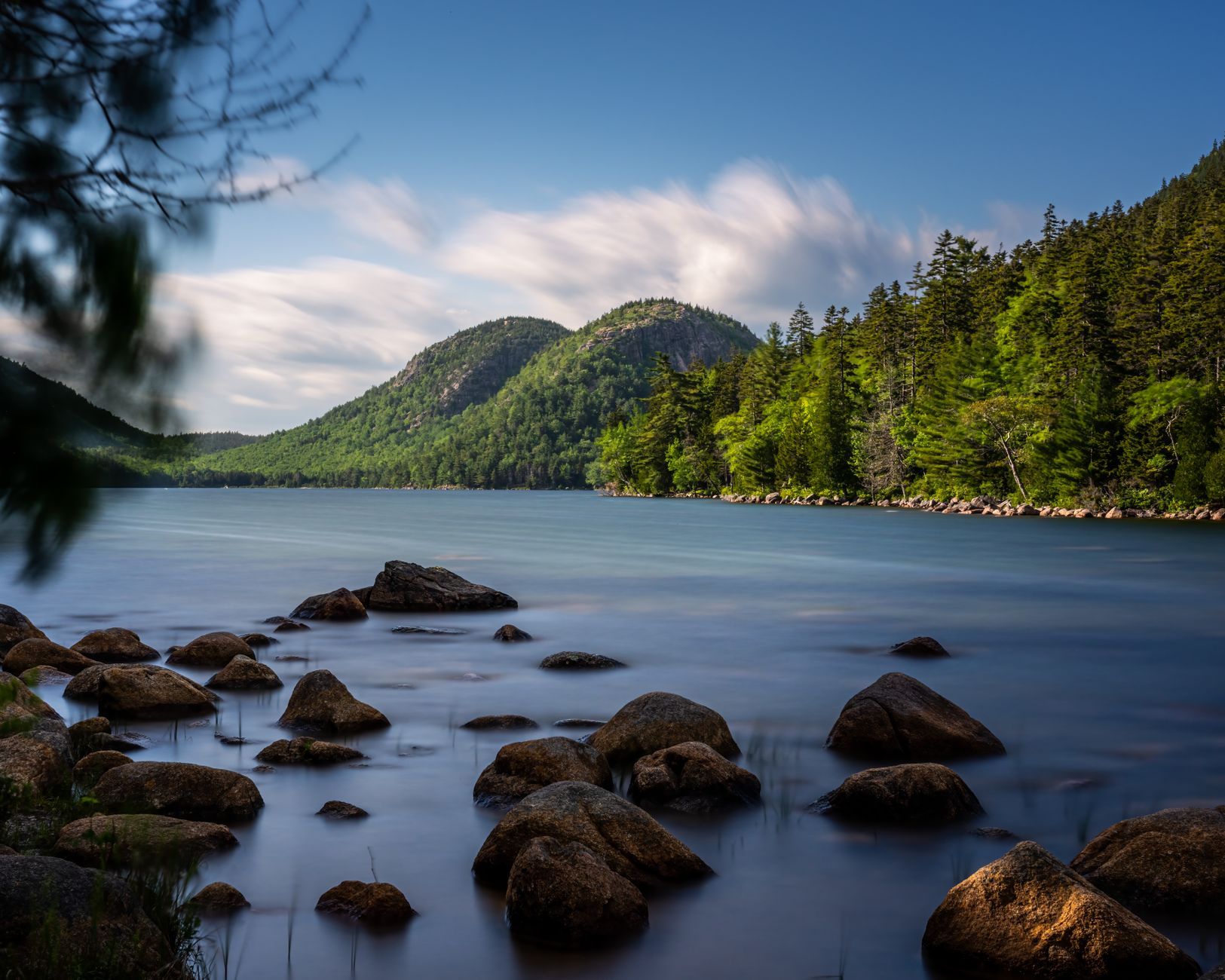 Serene landscape of Jordan Pond in Acadia National Park under a clear blue sky.
