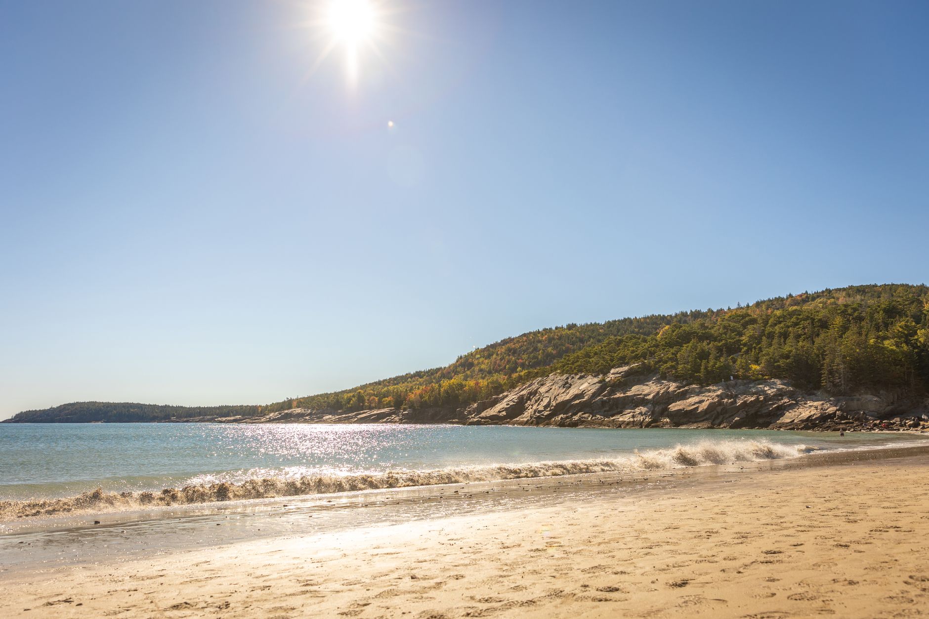 Beautiful sunlit beach with rocky coastline in Bar Harbor, Maine, USA.