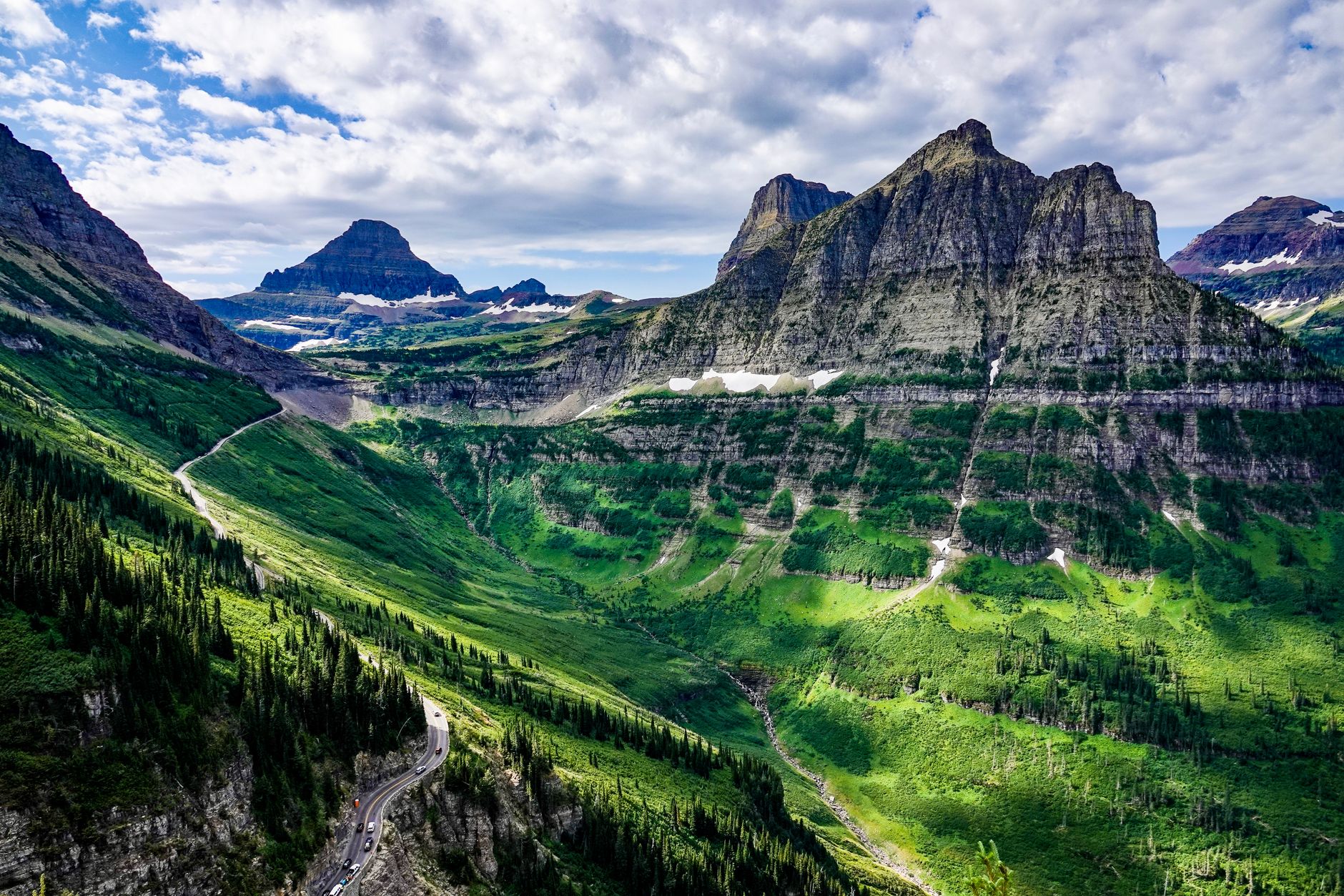 Breathtaking view of mountains and valleys in Glacier National Park under a vibrant sky.