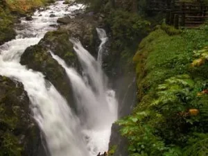 A steep waterfall between canyon walls covered in greenery.