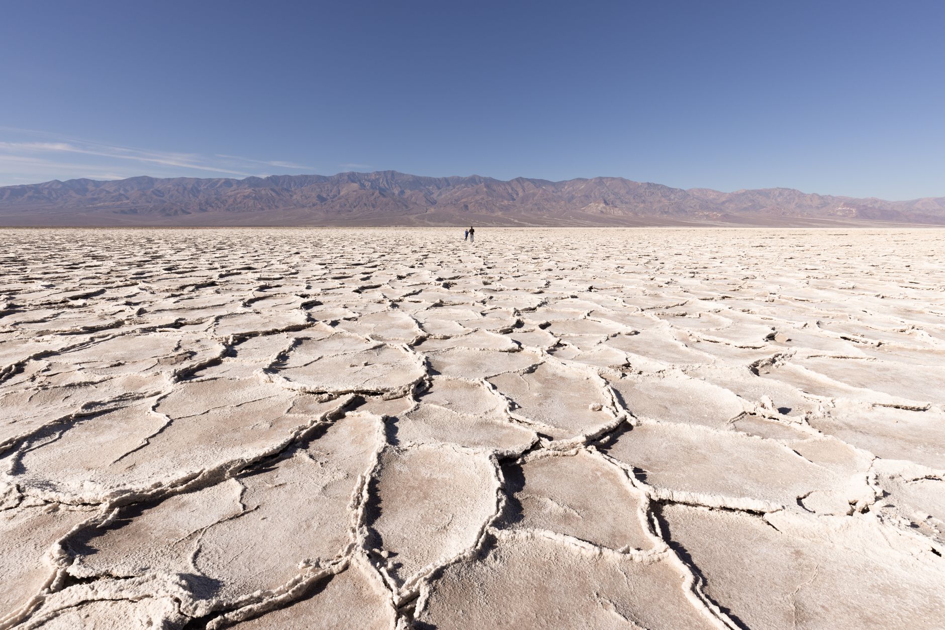 Expansive view of the salt flats in Badwater Basin, Death Valley, under a clear blue sky.