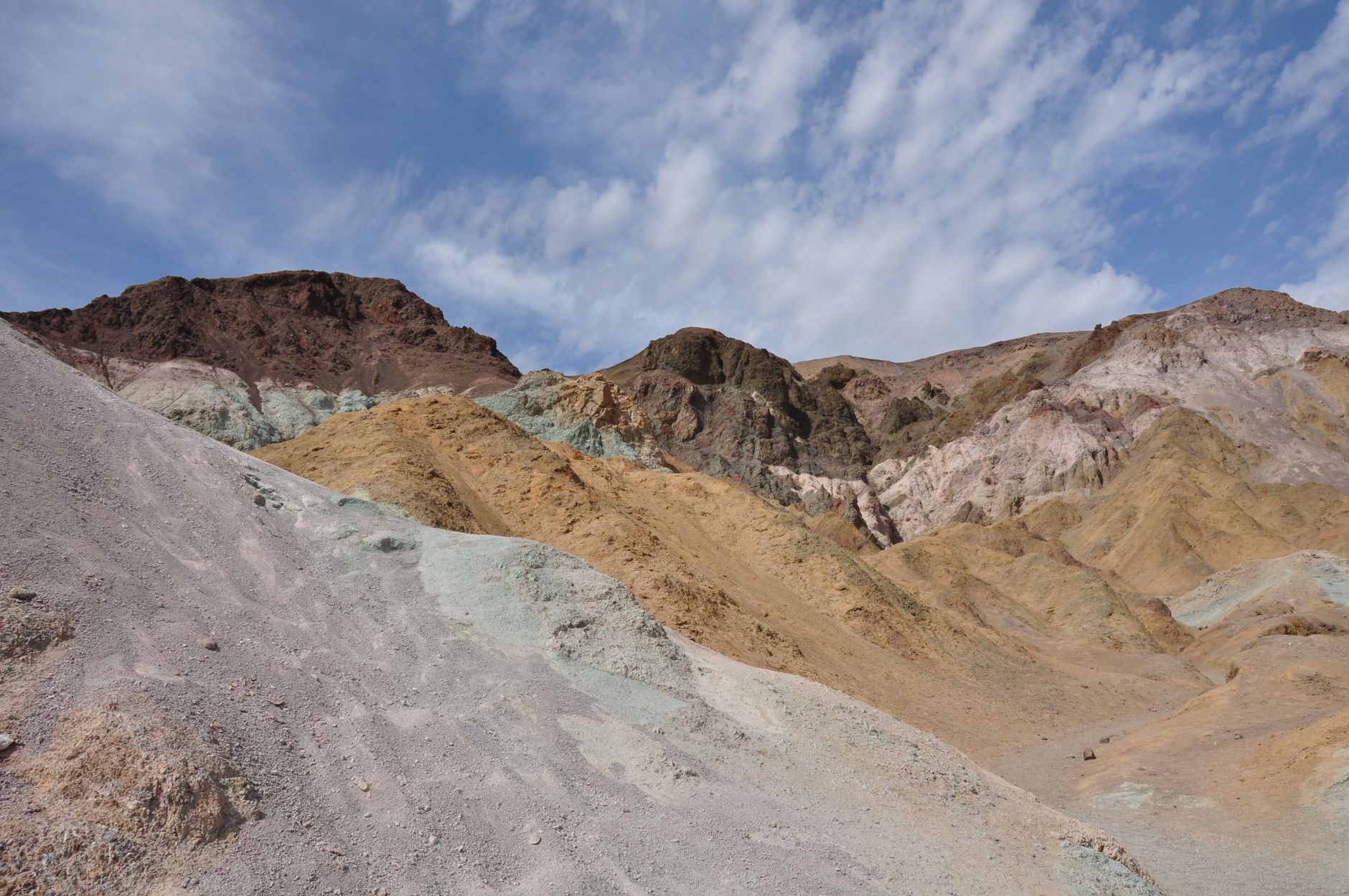 Colorful geological formations in Death Valley National Park under a clear blue sky.