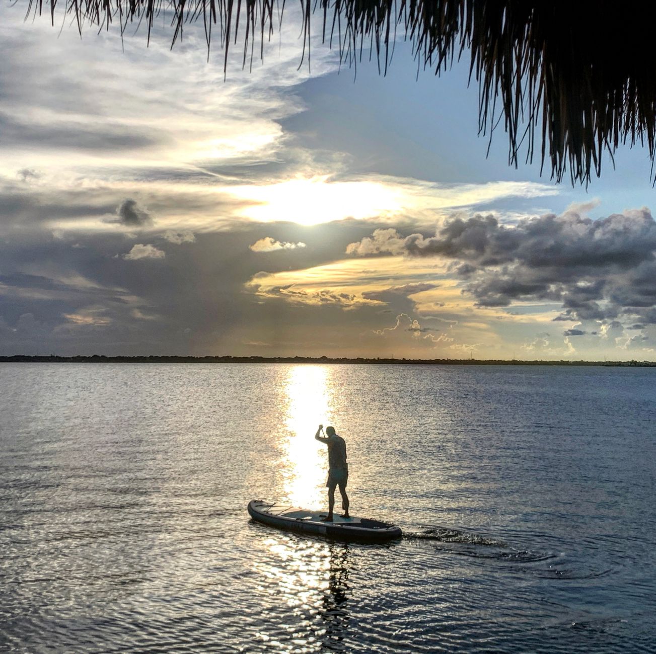 A silhouette of a man enjoying paddleboarding during a tranquil sunset at Jensen Beach, Florida.