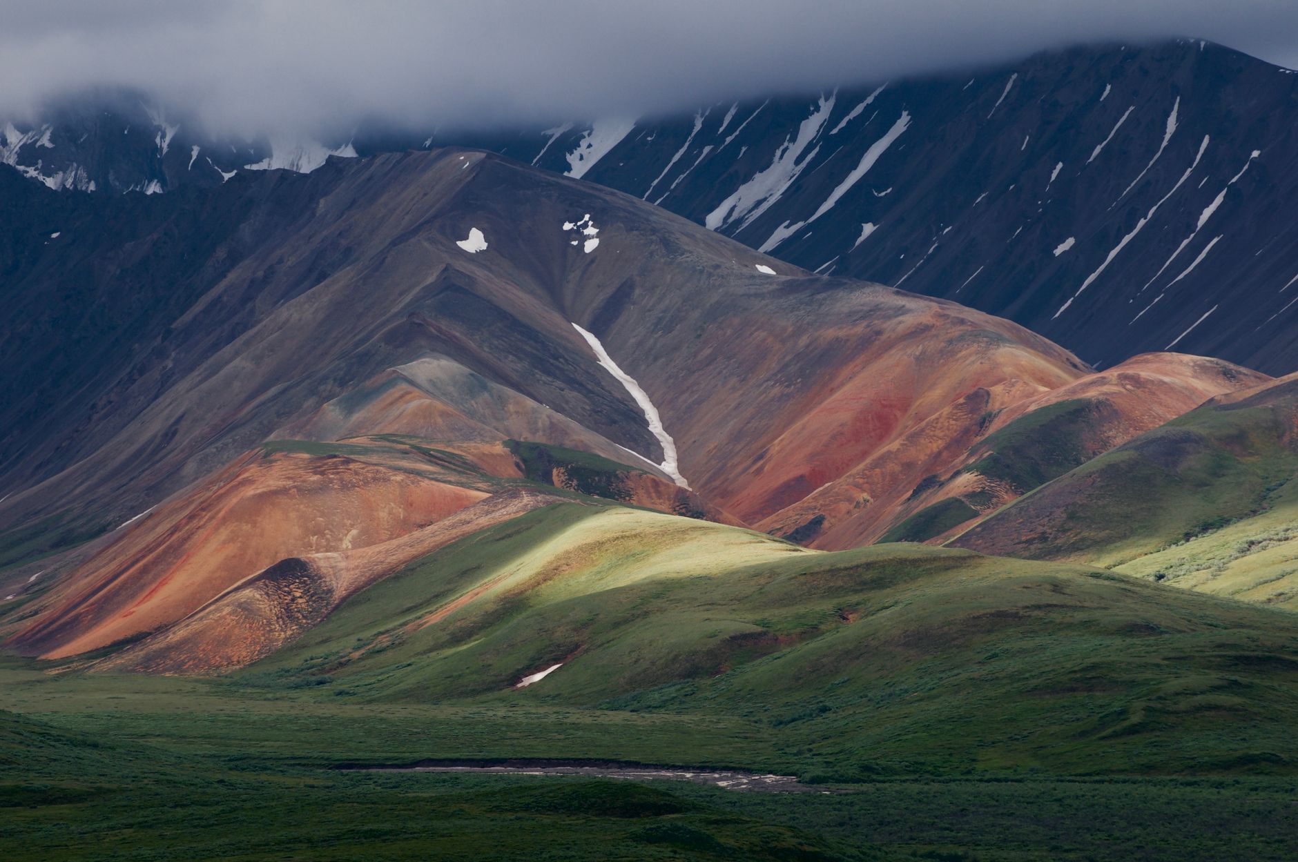 Breathtaking view of Alaska's multicolored mountains highlighting the unique landscape under a cloudy sky.