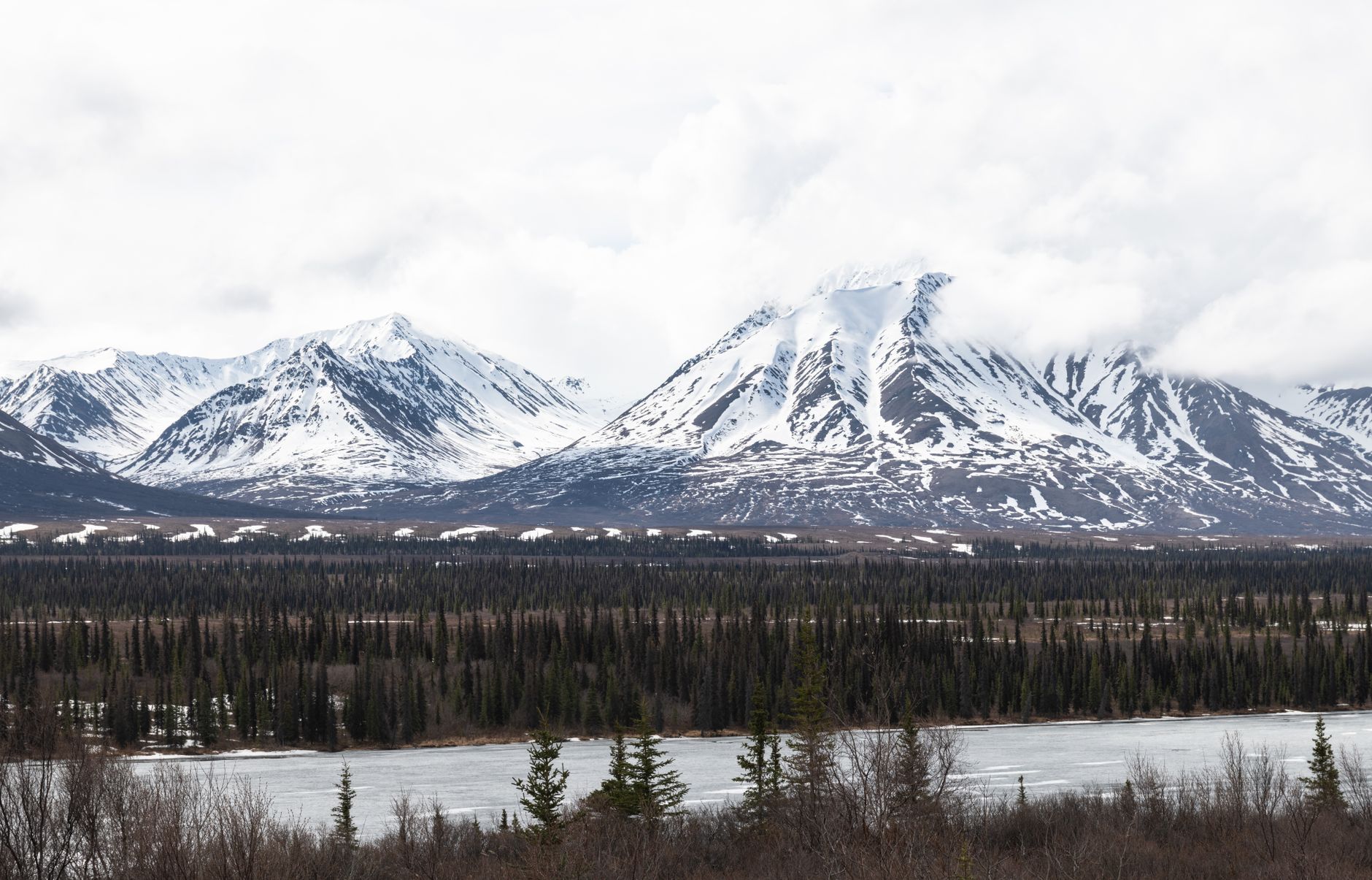 Serene winter landscape of snow-covered mountains and forests in Alaska, USA.