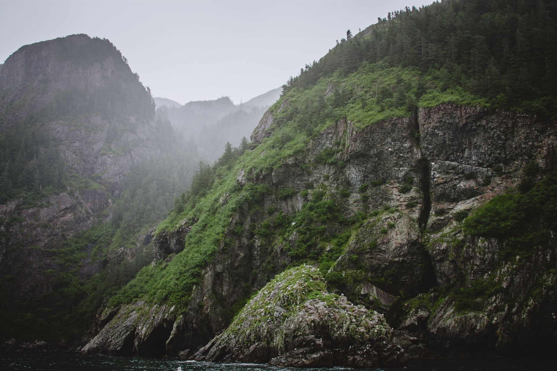 Explore a serene mountain landscape enveloped in mist, showcasing nature's untouched beauty and rugged cliffs.