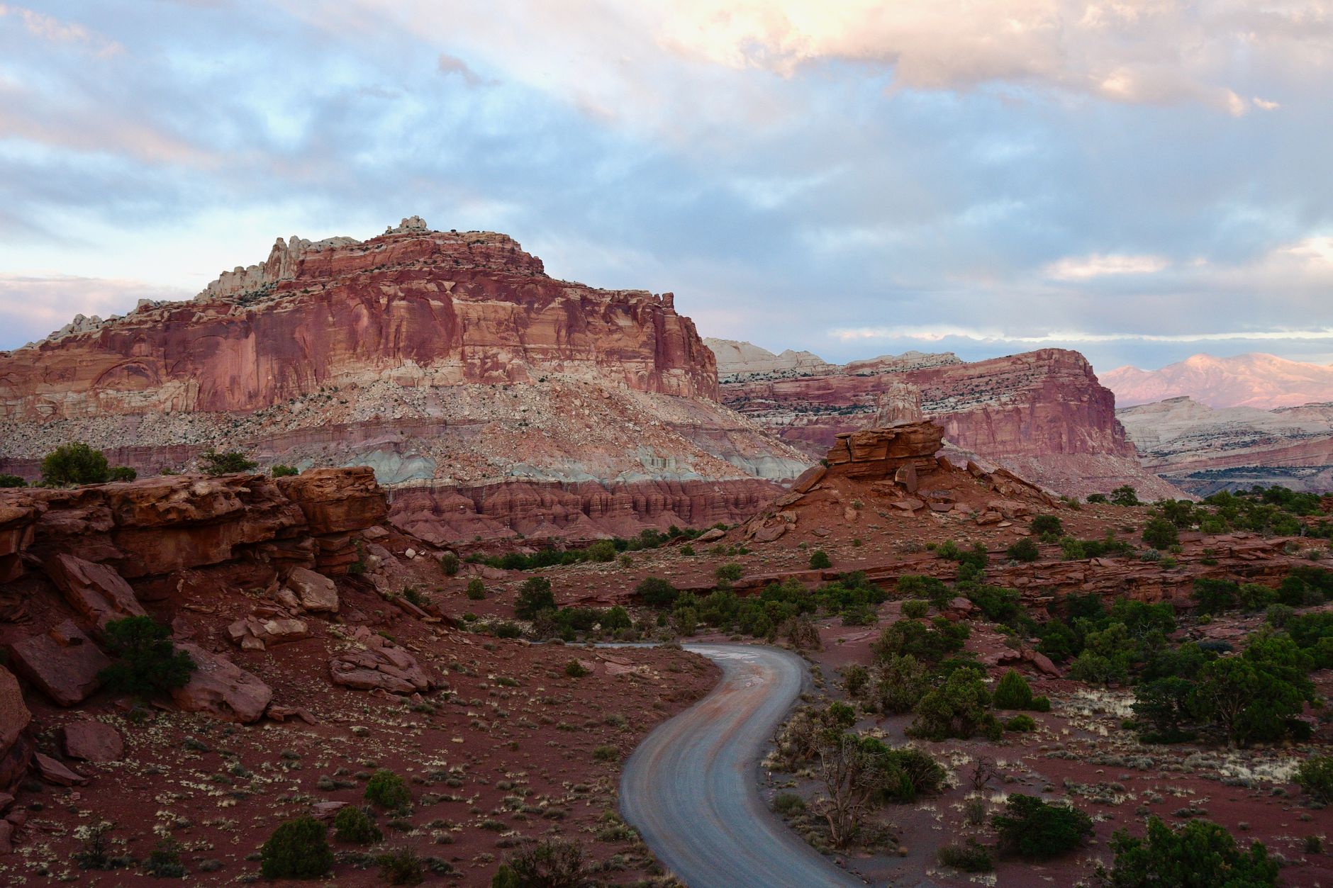 Scenic view of a winding road amidst the striking red rock formations of Capitol Reef National Park at sunset.