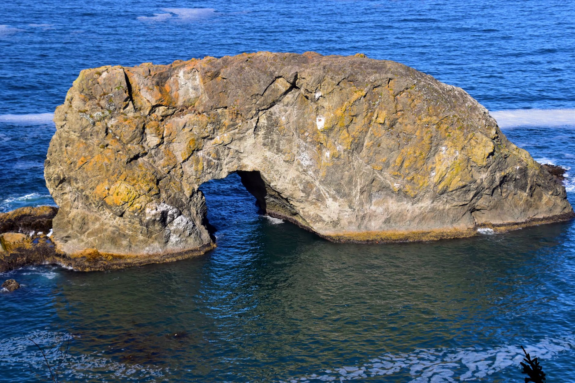 A striking natural rock arch stands against the deep blue ocean, offering a scenic coastal view.