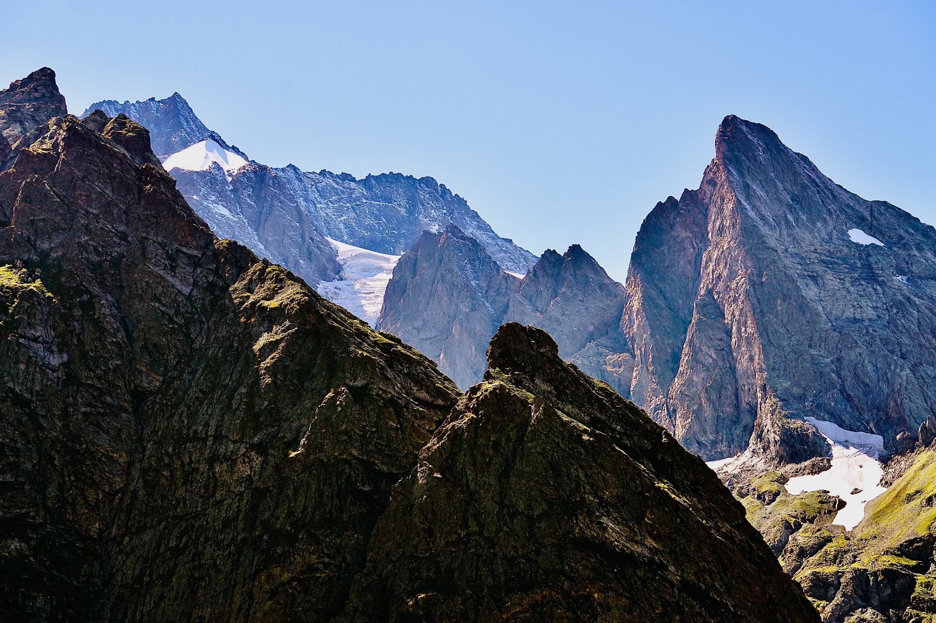 Stunning view of rugged mountain peaks with snow patches under a clear blue sky.