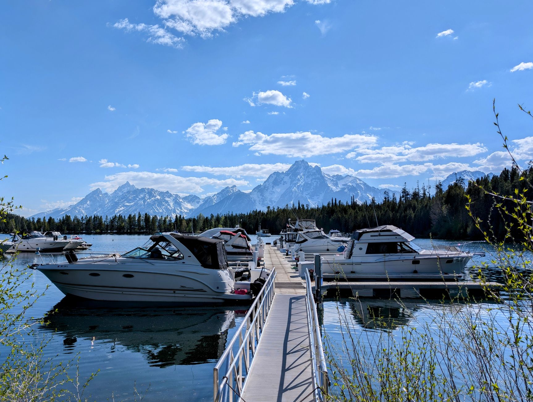 Scenic view of boats docked at Colter Bay Village marina with majestic mountain backdrop.