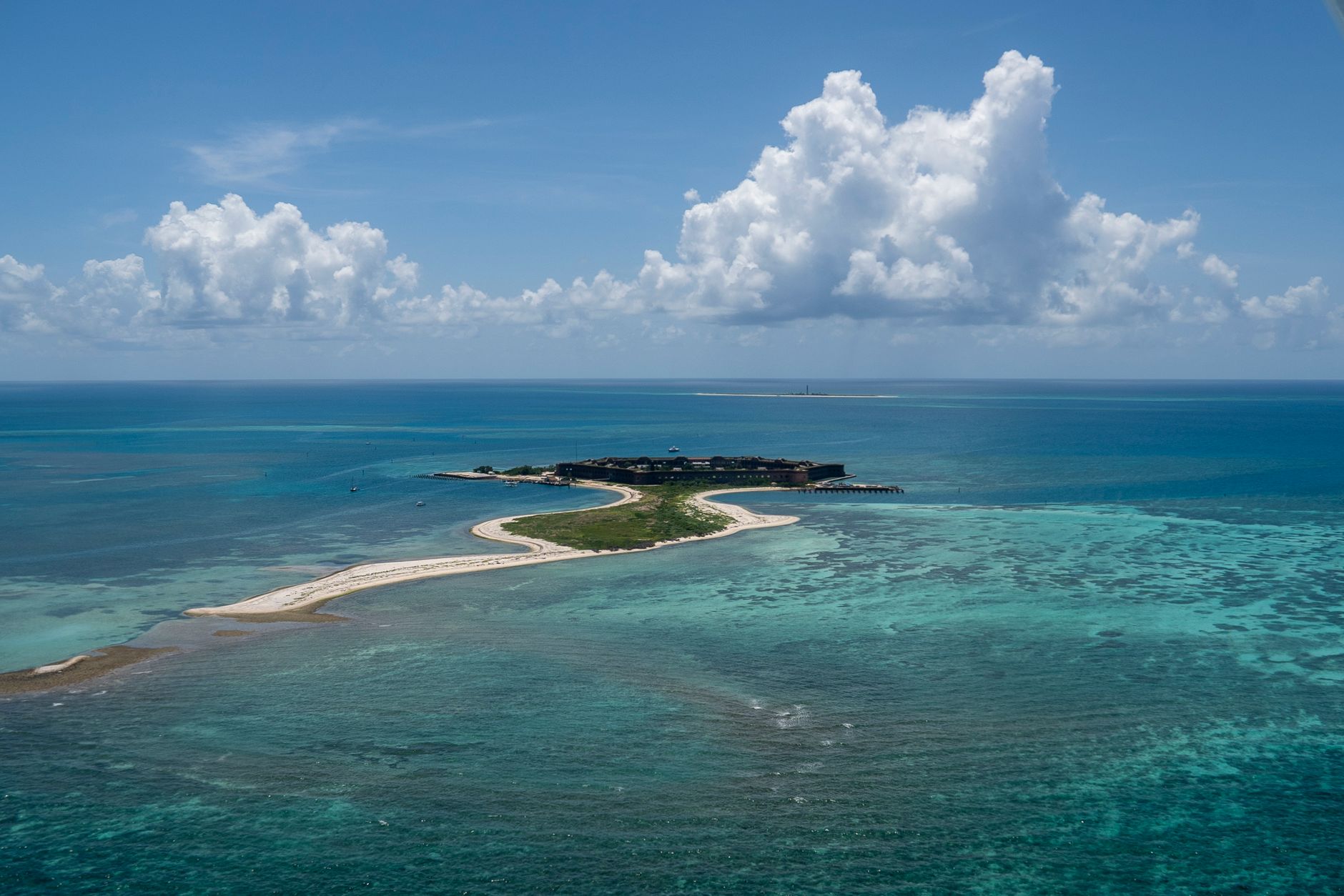 Stunning aerial view of a tropical island in Key West, FL, surrounded by turquoise waters under a bright sky.