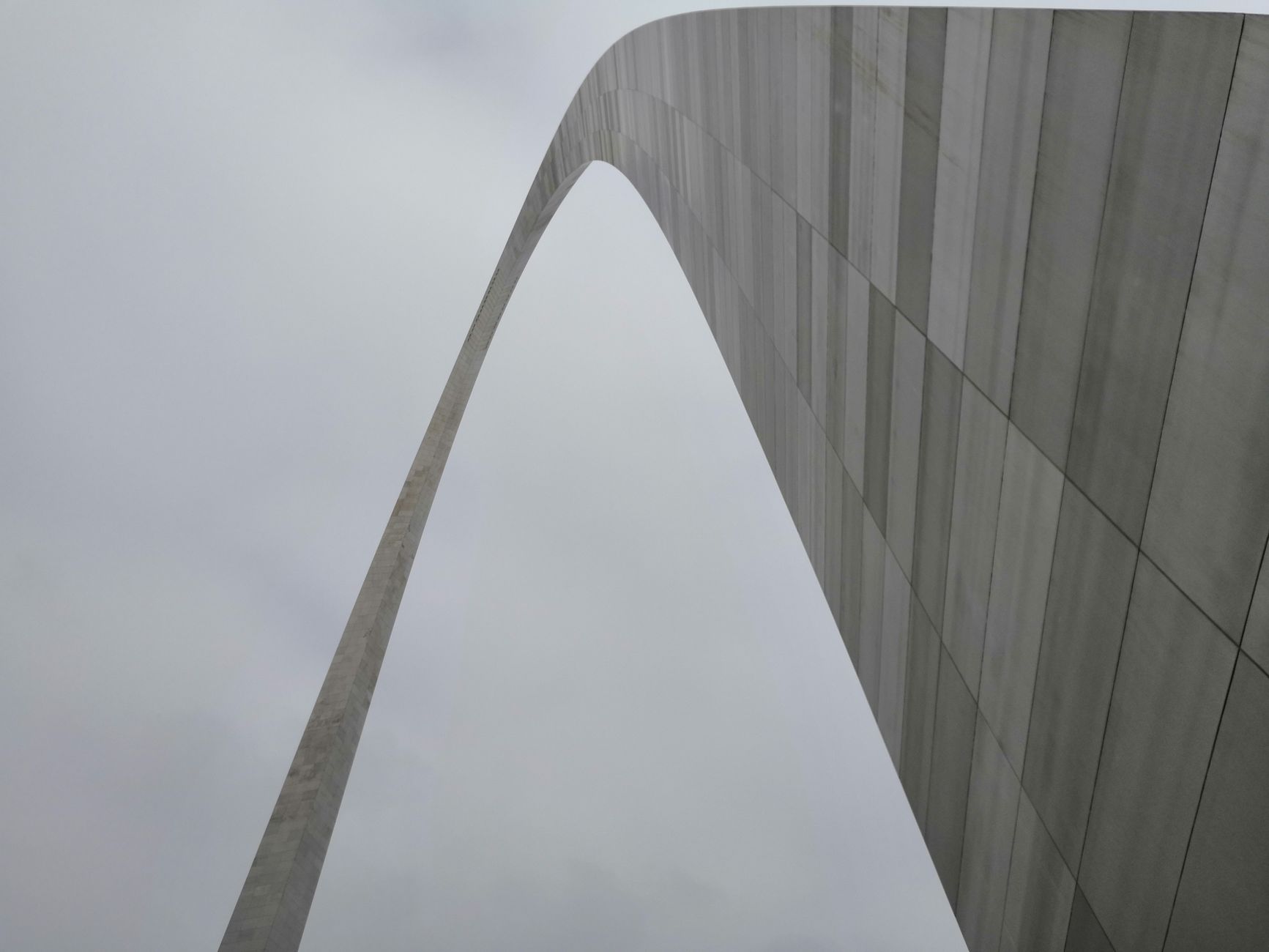 From below exterior of arch of contemporary building located under cloudy sky in gloomy weather