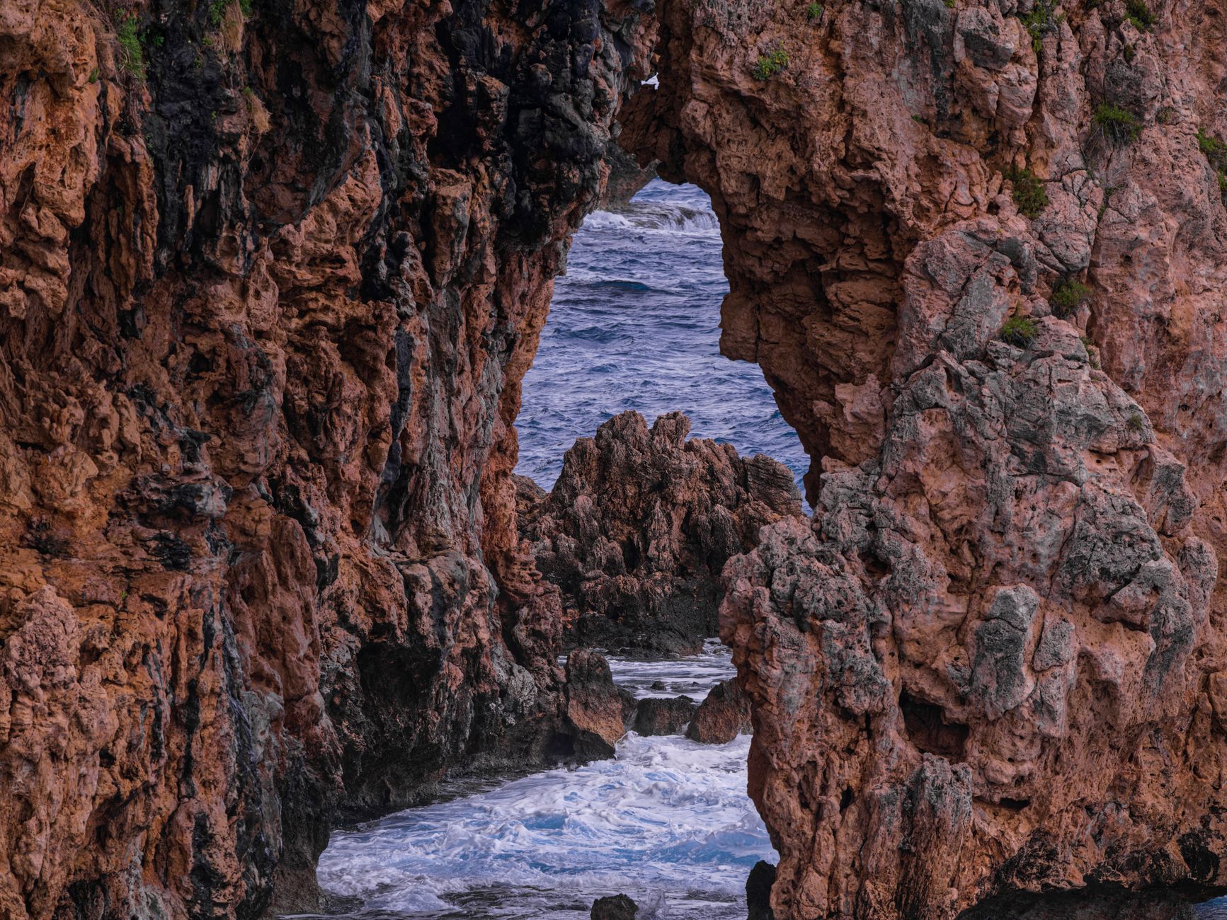 Stunning view of ocean waves through a rocky archway, showcasing nature's beauty and power.