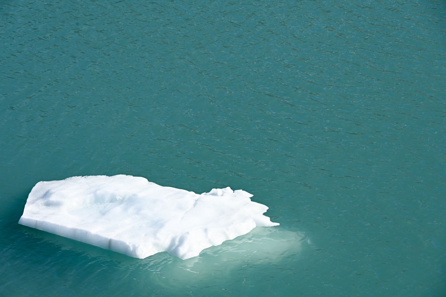 A serene view of a floating iceberg on turquoise waters in Alaska.