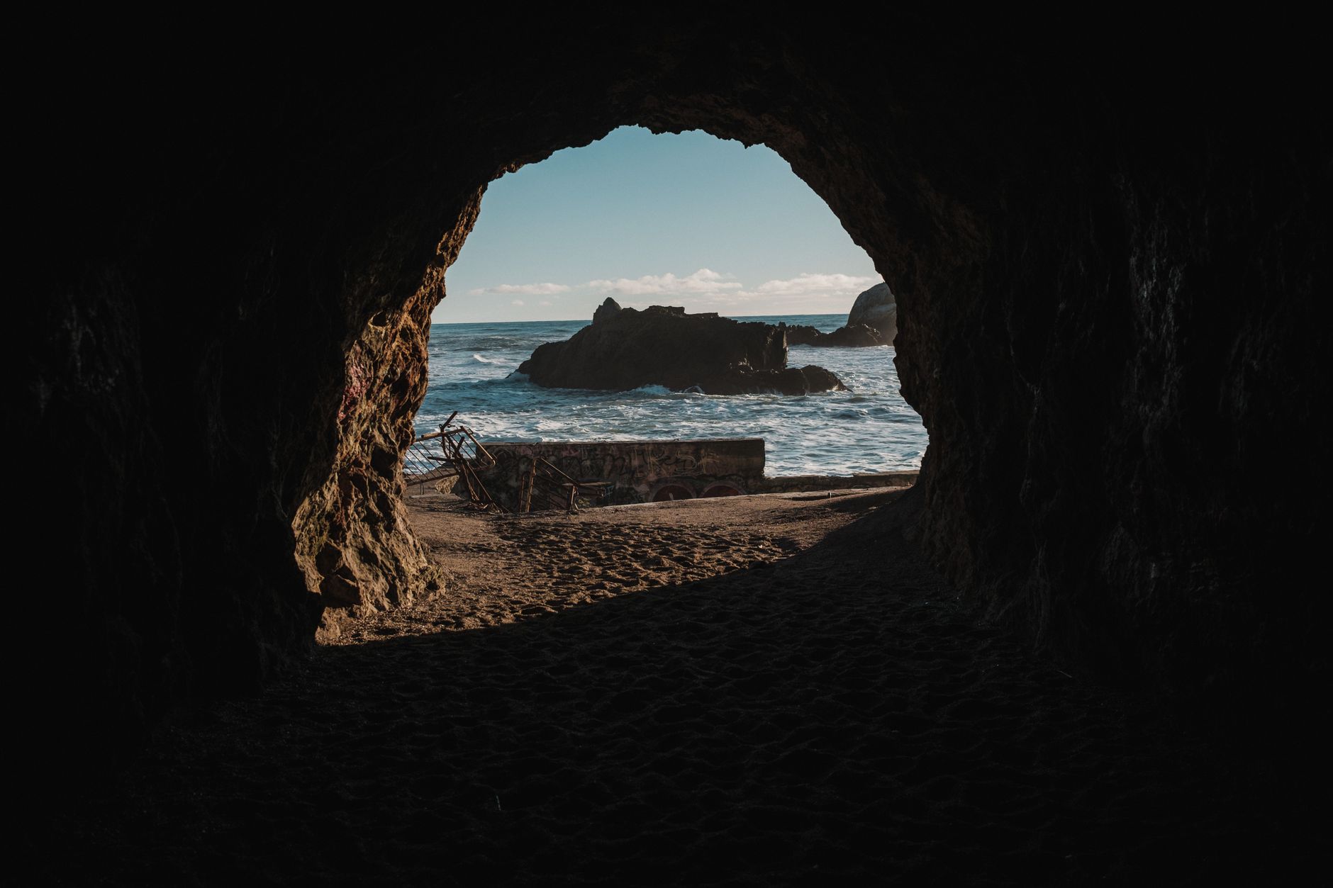 Scenic view from a coastal cave with ocean waves and setting sun creating a captivating seascape.