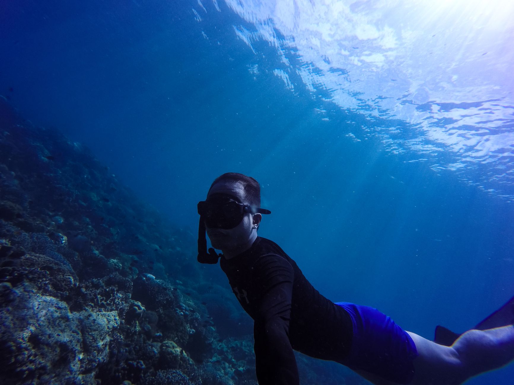 Diver exploring vibrant coral reef in clear blue underwater scenery, capturing the thrill of snorkeling.