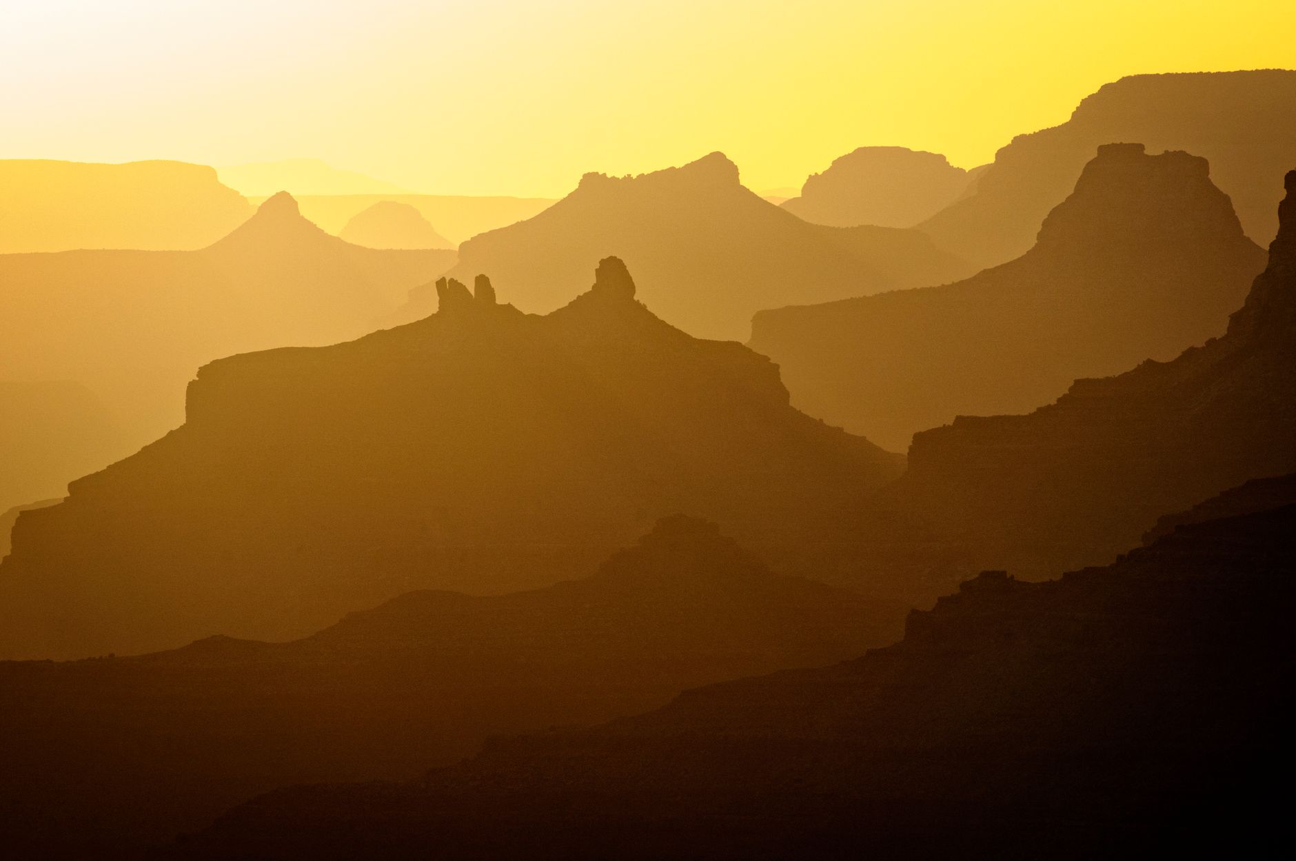 Golden hour at Grand Canyon showcasing dramatic mountain silhouettes against a vivid sunset.
