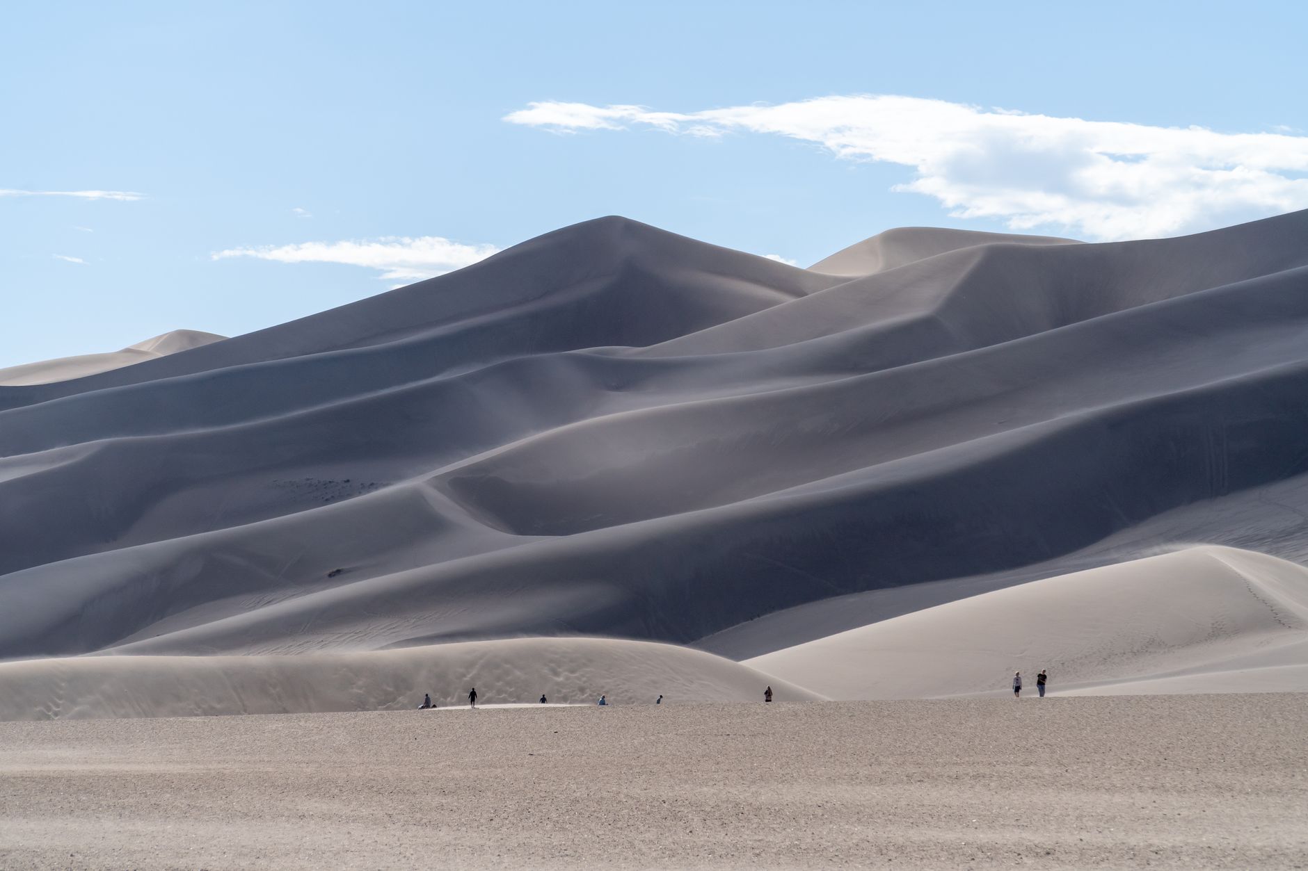 Explore the stunning sand dunes in Colorado's Great Sand Dunes National Park with people hiking below.