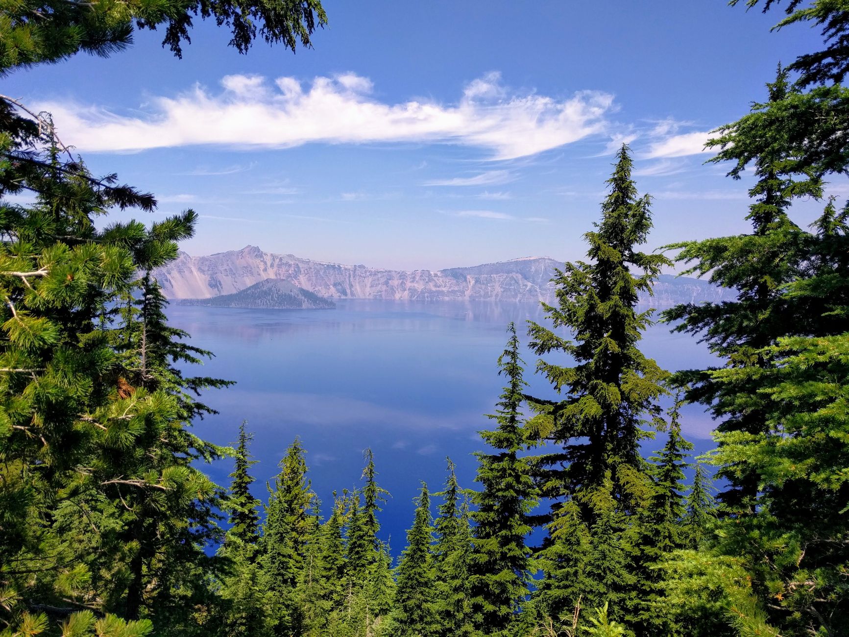 A breathtaking view of Crater Lake framed by lush trees under a clear blue sky.