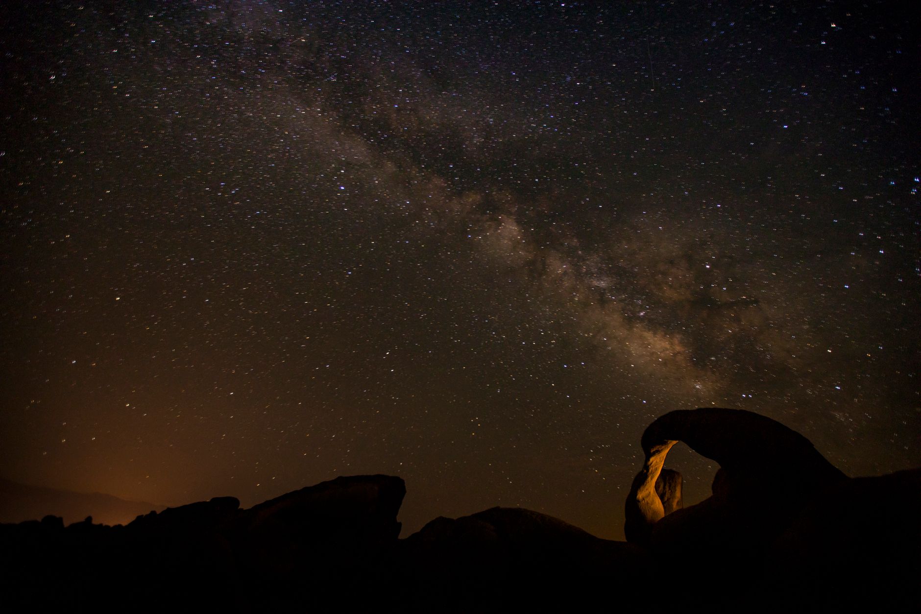 A breathtaking view of the Milky Way galaxy above a natural rock formation under clear night skies.