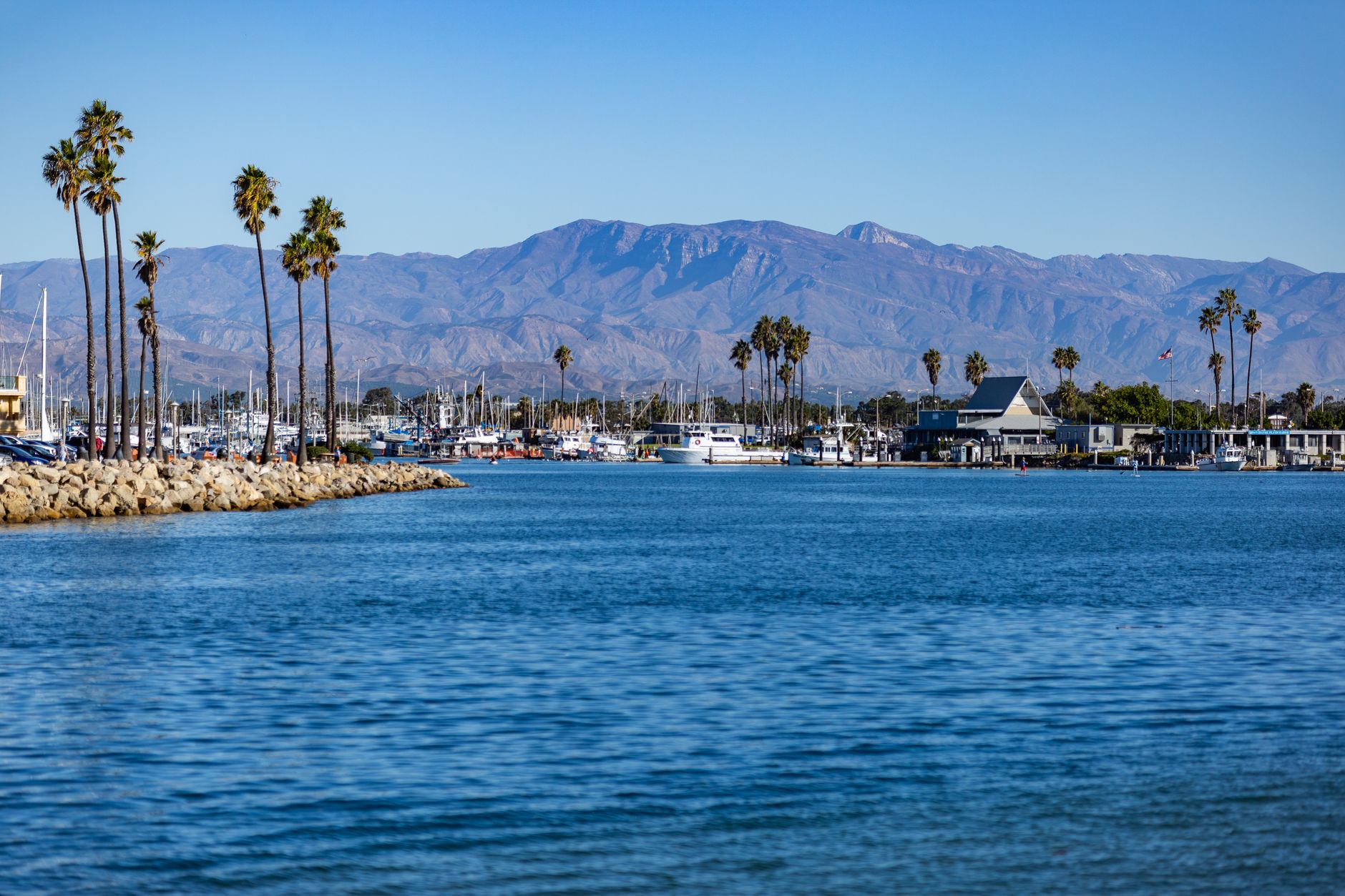 Beautiful view of Channel Islands Harbor in Oxnard, CA with palm trees and mountains in the background.