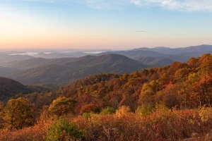 A view from an overlook down into a valley below filled with fall colors of red and orange.